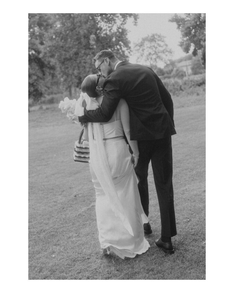 Candid photo of elegant Bride and Groom walking together laughing. Black and White classic image with a vintage feel bringing out all the emotion, in London, UK. Photo by London Wedding Photographer, Pia Bacino