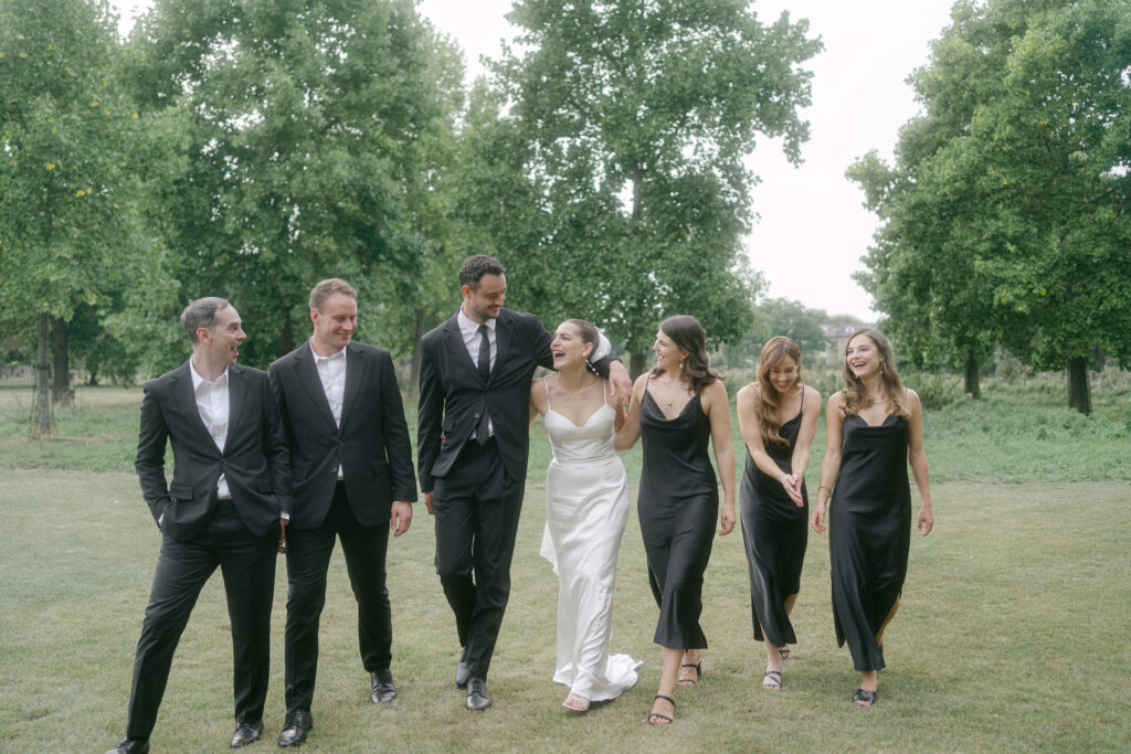 Bridal party walking with linked arms laughing. Photo by London Wedding Photographer, Pia Bacino